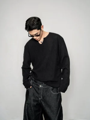 Black men's relaxed notch neck knit sweater styled with dark wide leg denim in a minimalist Seoul streetwear studio look
