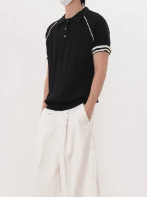 Men's black retro contrast trim ribbed knit polo shirt left side view with white wide-leg pants