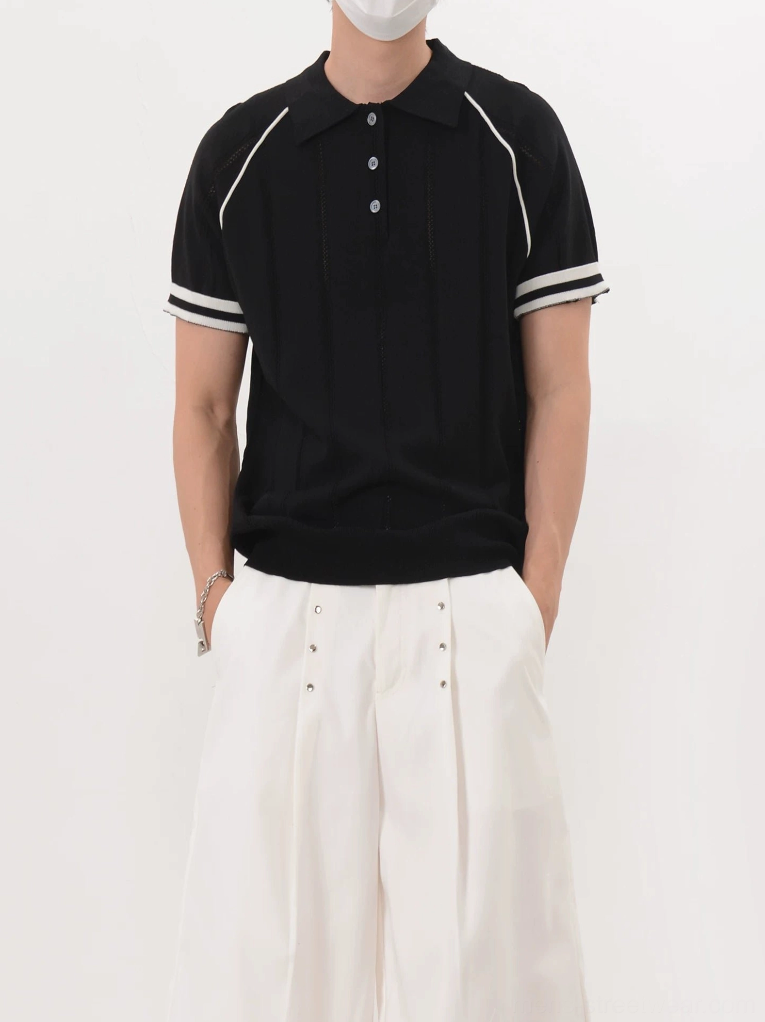 Men's black retro knit polo shirt with vertical textured stripes and contrast cuff trim three-quarter view