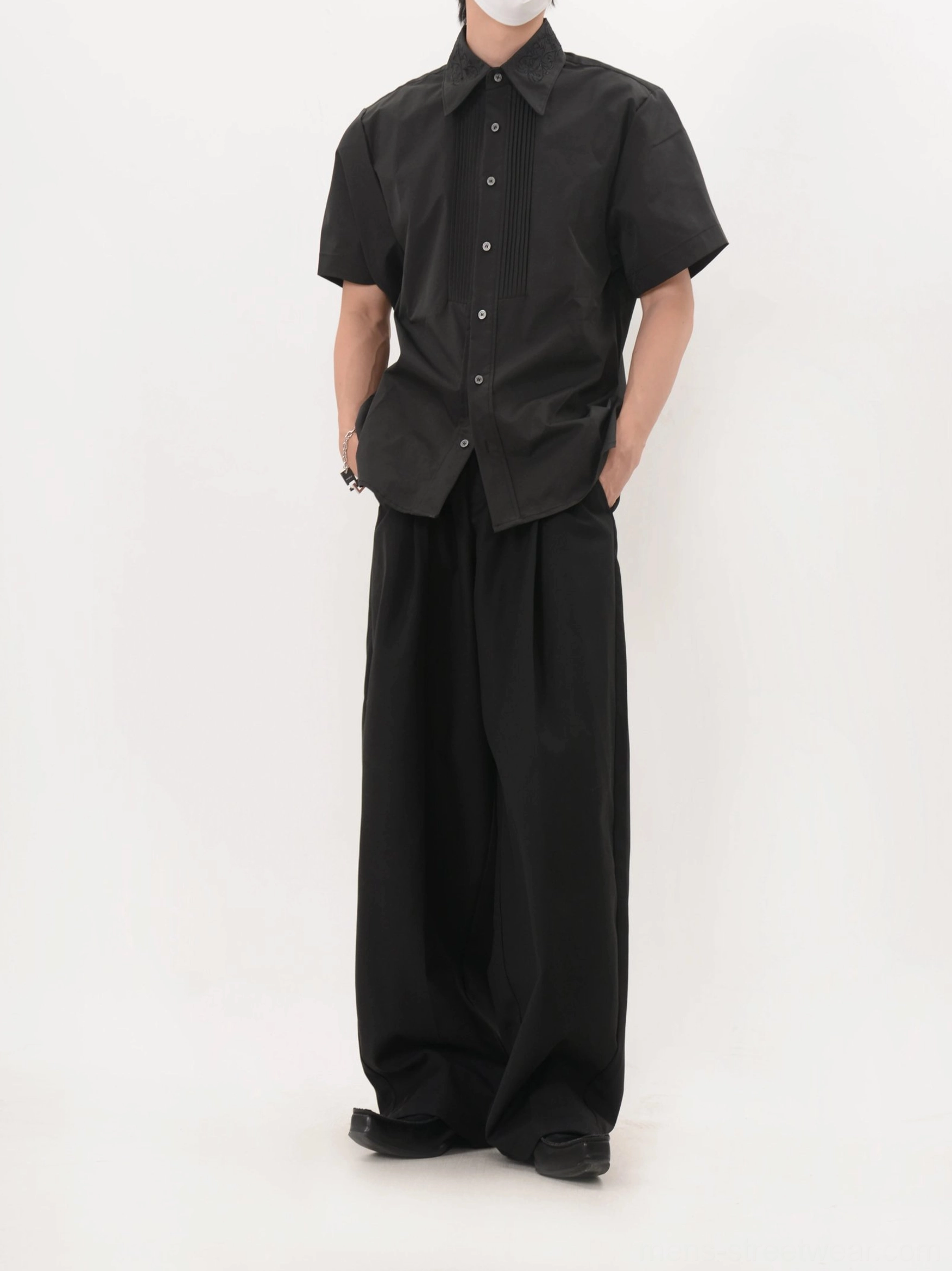 Full front view of men's black short sleeve pleated tuxedo shirt with wide leg trousers and leather shoes