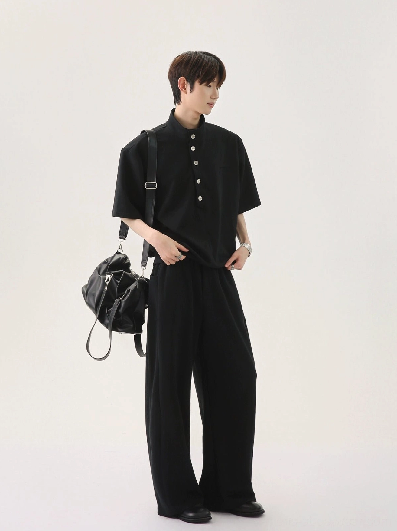 Men's black stand collar polo and wide-leg pants set in relaxed Korean streetwear style with leather shoulder bag