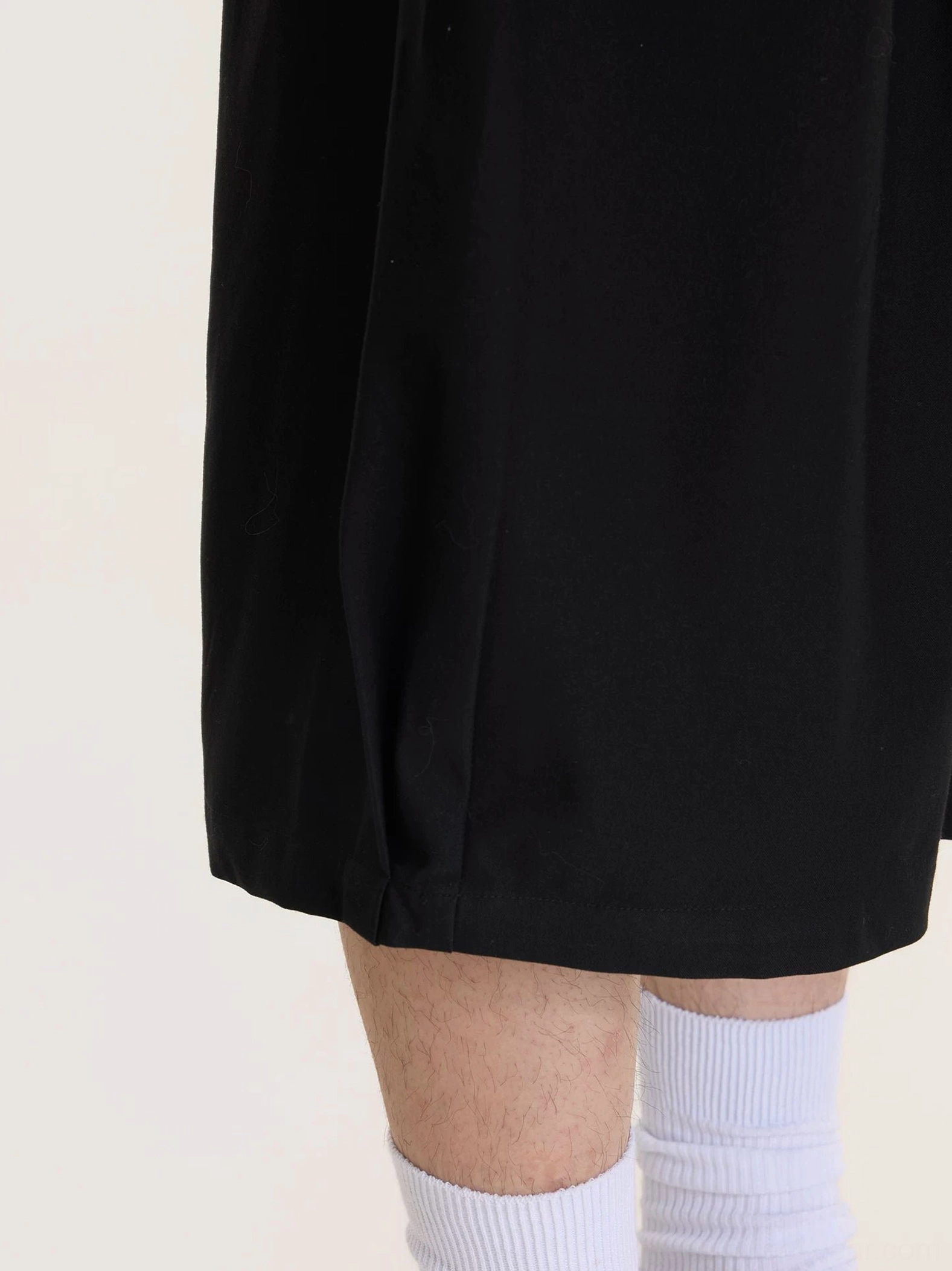 Close-up of smooth black culottes hem showing the straight wide-leg cropped cut and minimalist streetwear construction