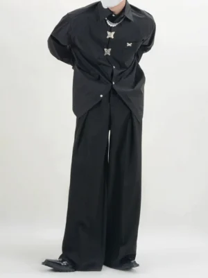 Men's black wide-leg pleated trousers styled with silver jewelry and a statement shirt, highlighting the relaxed oversized silhouette and avant-garde Korean streetwear aesthetic