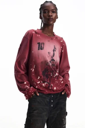 Men's burgundy vintage distressed graphic long-sleeve streetwear T-shirt in a three-quarter front view with number 10 artwork, white ink splatters, worn neckline, and dark cargo pants
