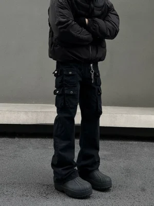 Front view of men’s carbon gray multi-pocket cargo jeans with button flap pockets, flared legs, and chunky black boots