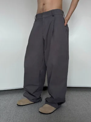 Front low-angle view of men's charcoal grey pleated wide-leg trousers with a high-rise waist and relaxed full-length silhouette