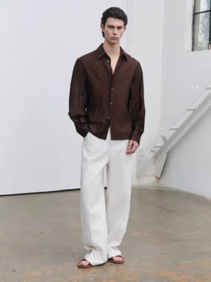 Men's dark brown semi-sheer fluid sheen tailored shirt shown from the front with pointed collar, button placket, long sleeves, and softly shaped waist in a Korean streetwear outfit