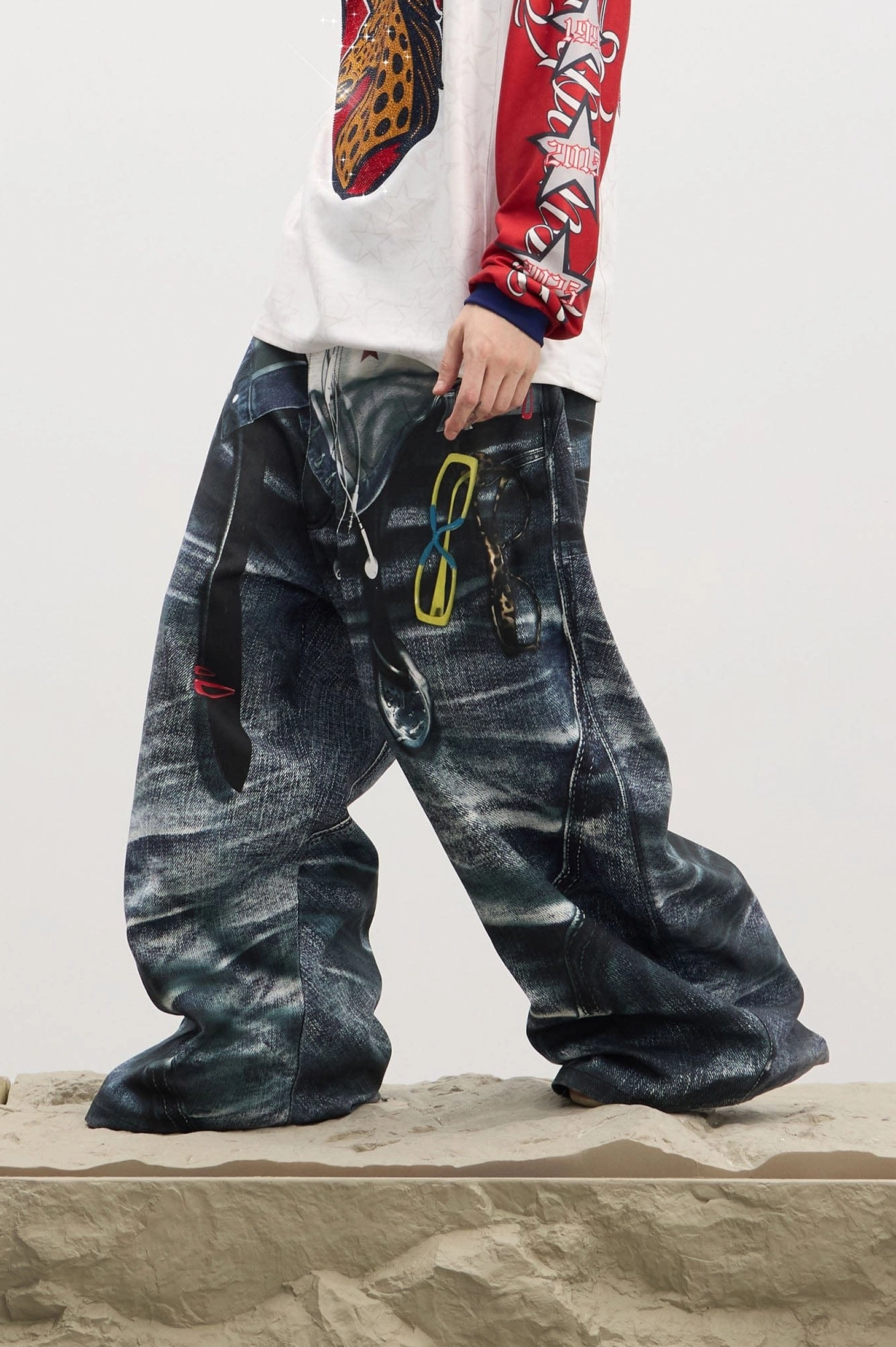 Side detail of men's dark denim sagging-illusion jeans with hanging metal clips, relaxed wide-leg cut, and oversized Korean streetwear silhouette