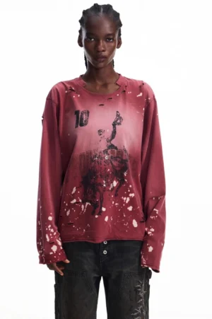Front view of a men's faded burgundy ink-washed long-sleeve graphic T-shirt with number 10 print, abstract artwork, white splatter details, and distressed sleeve trims