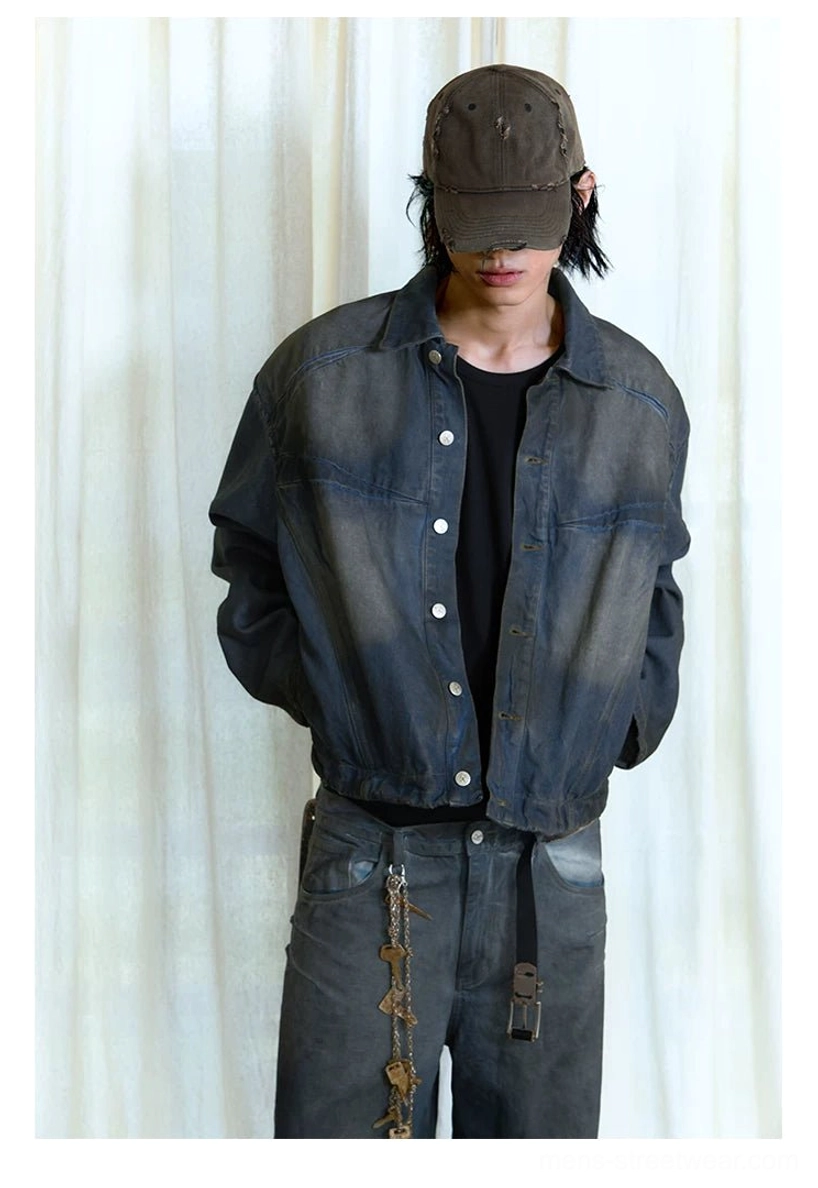 Male model in a faded indigo panel denim trucker streetwear jacket showing cropped relaxed fit and metal snap front closure