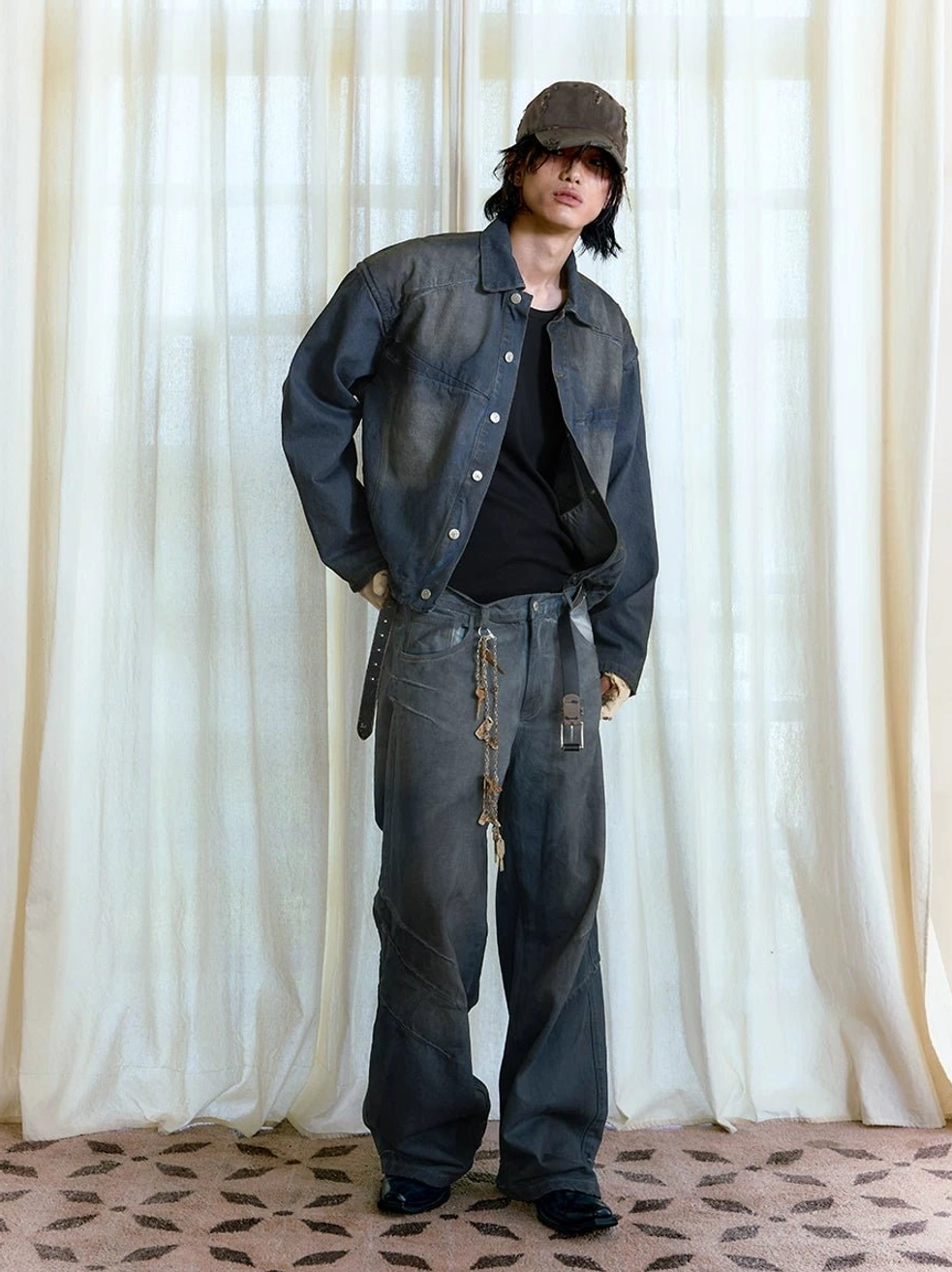 Side view of male model styling a cropped faded indigo panel denim trucker jacket with matching wide-leg denim pants