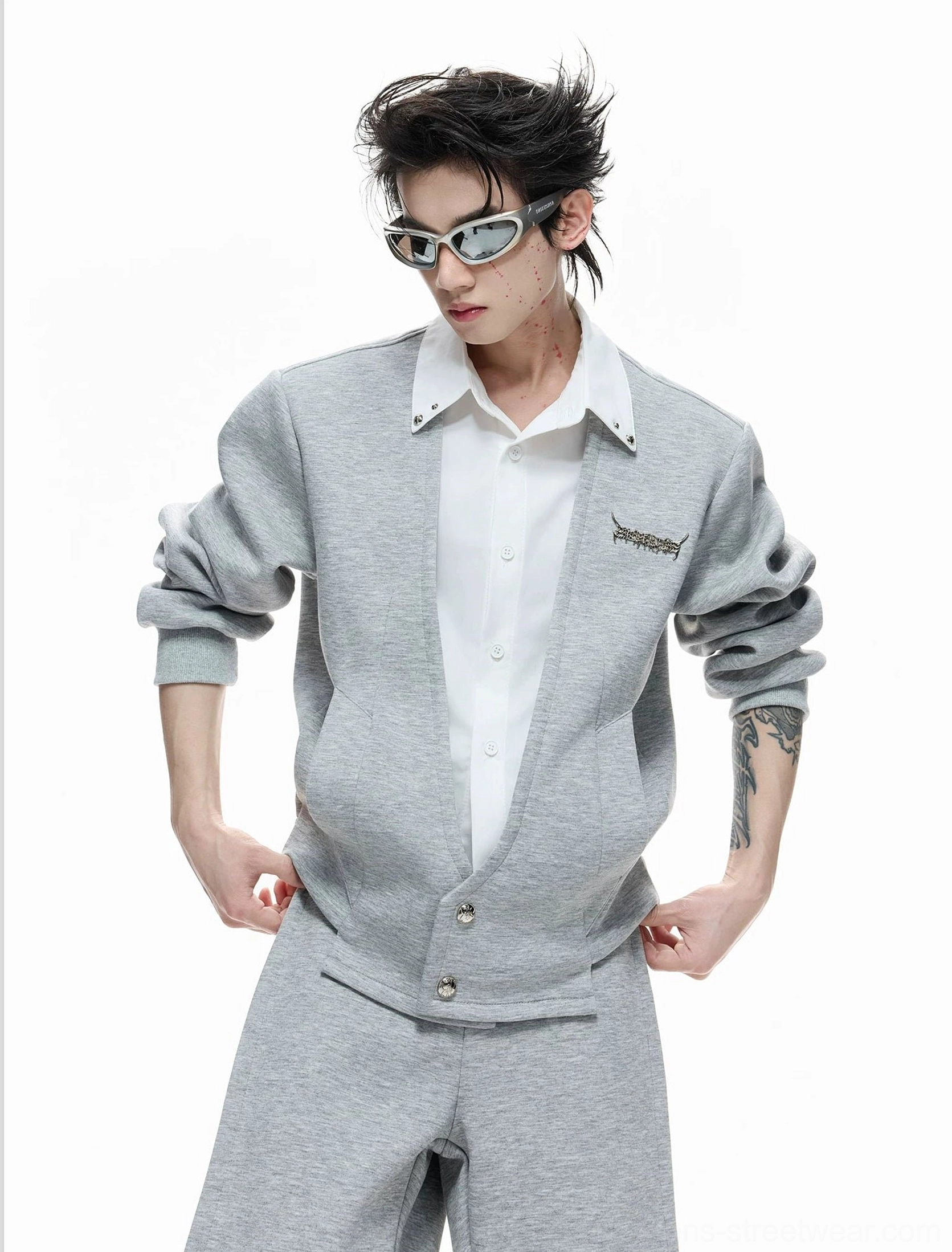 Front detail of men's grey faux-twinset cardigan shirt with button closure, rolled sleeves, and embroidered chest accent