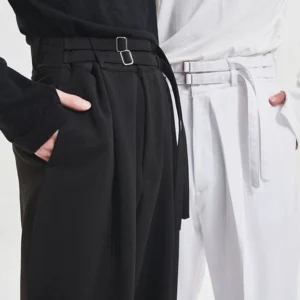 Close-up of black and milky high waist double buckle wide leg pleated trousers showing integrated belt and smooth tailored fabric