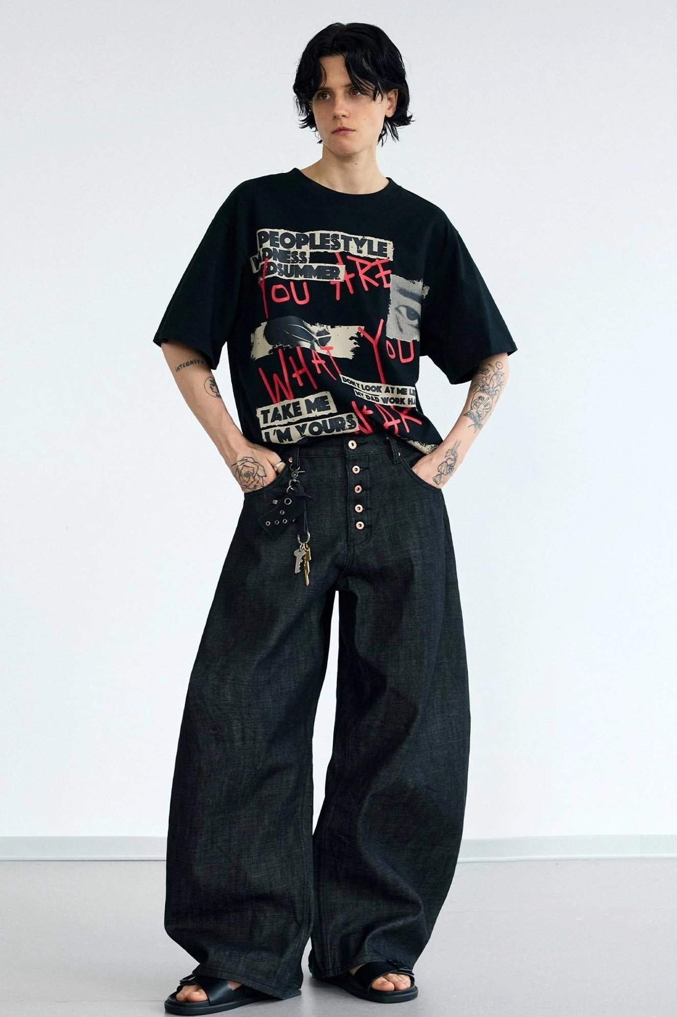 Front full-body view of men's high-waisted curved wide-leg black jeans with functional button fly and dark washed denim finish