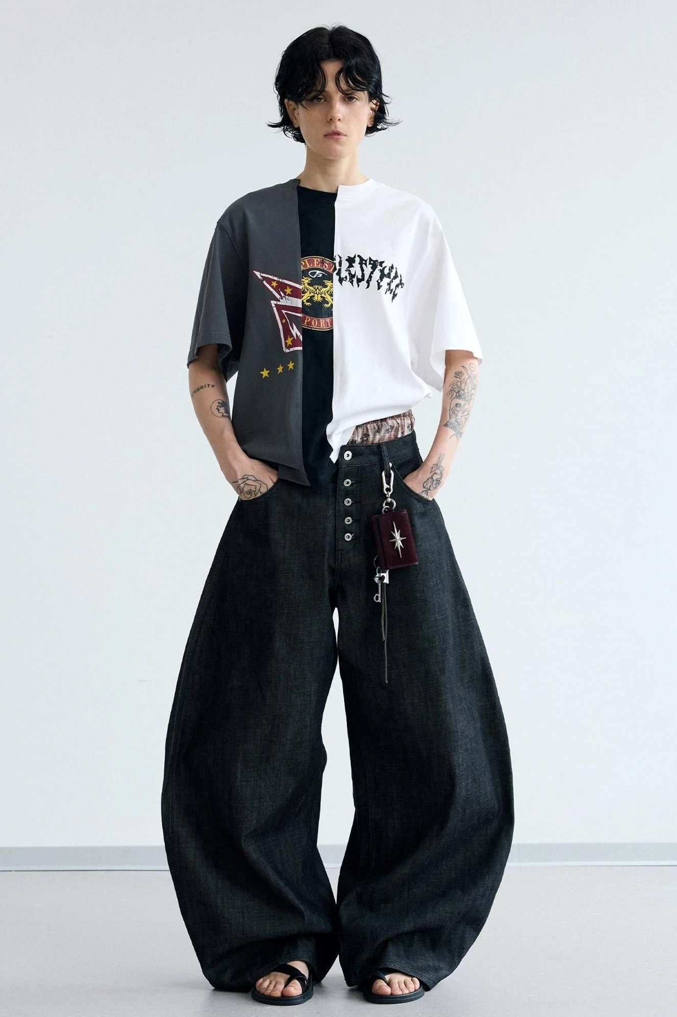 Front view of men's high-waisted wide-leg curved jeans with hands in pockets and attached denim keychain accessory