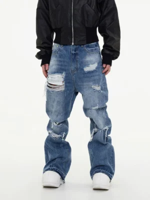 Men's light wash ripped baggy jeans front full body view with wide leg distressed blue denim and white sneakers