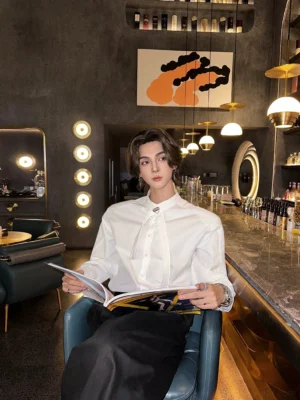 Men's minimalist white buckle tie dress shirt with metal neck fastening styled in an upscale hotel bar lounge