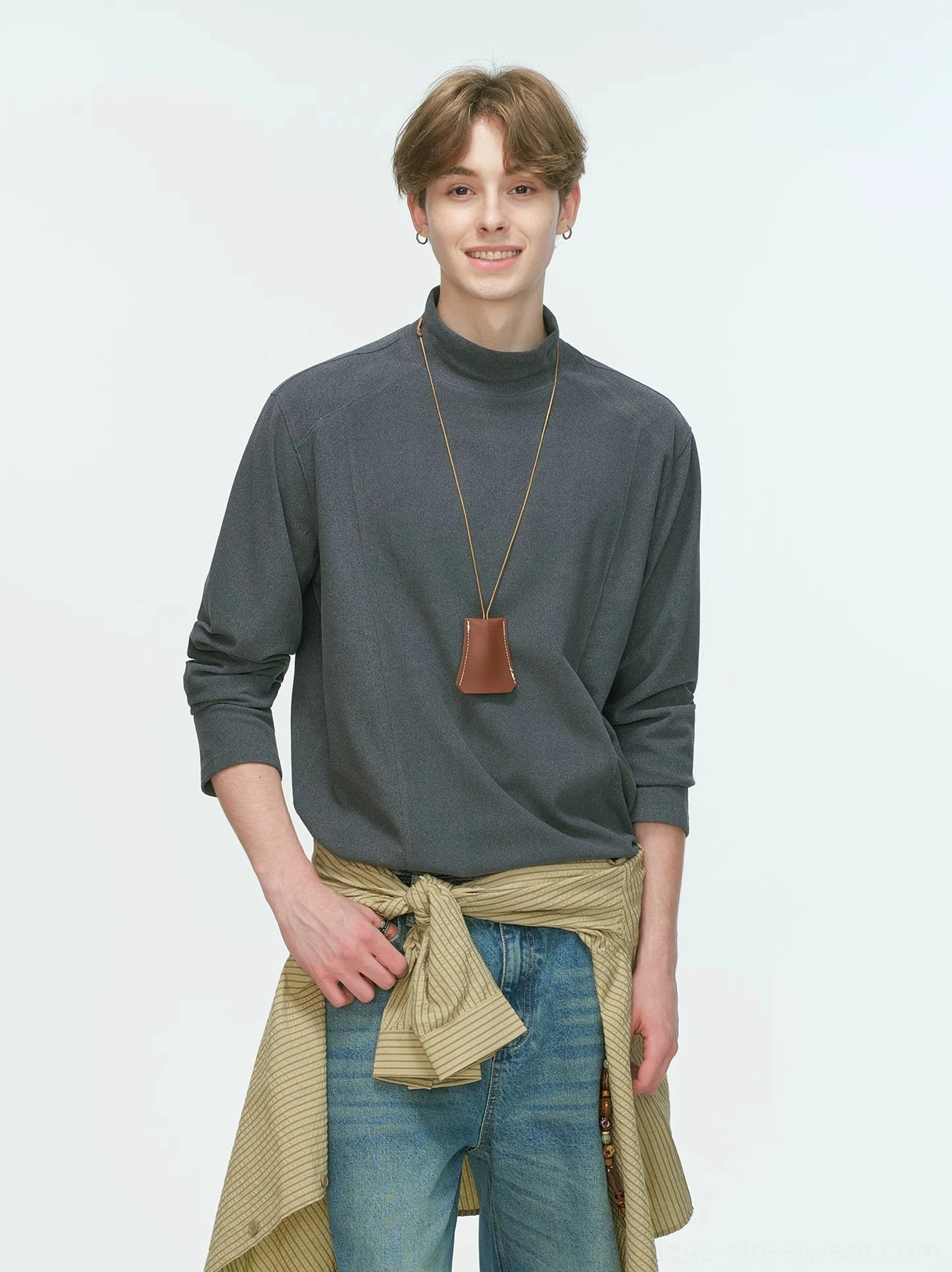 Charcoal gray men's mock neck long sleeve top styled with a leather pendant necklace and shirt tied around the waist in a Korean streetwear outfit