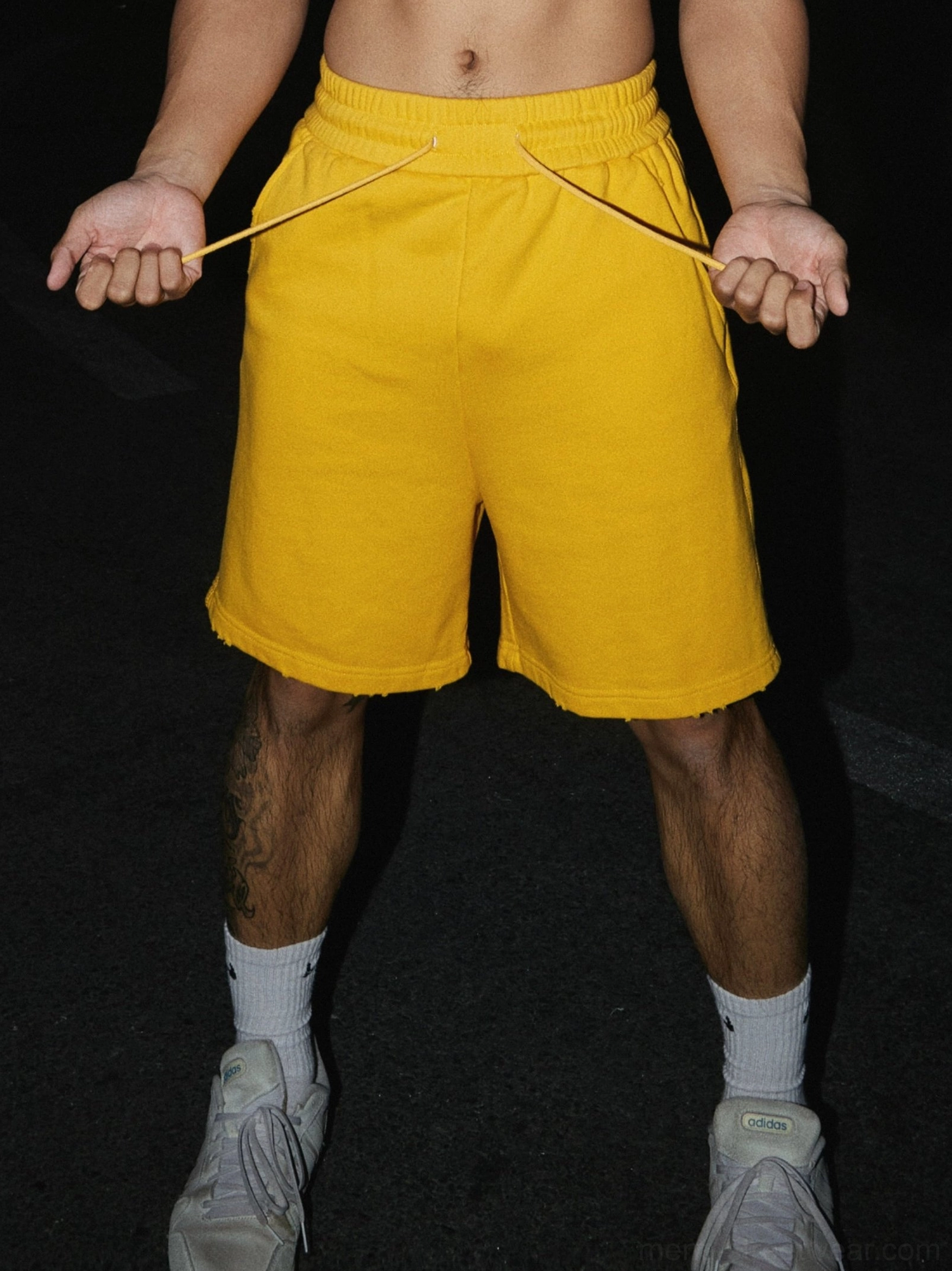 Men's mustard raw hem shorts featuring an adjustable drawstring elastic waist and relaxed athletic streetwear fit