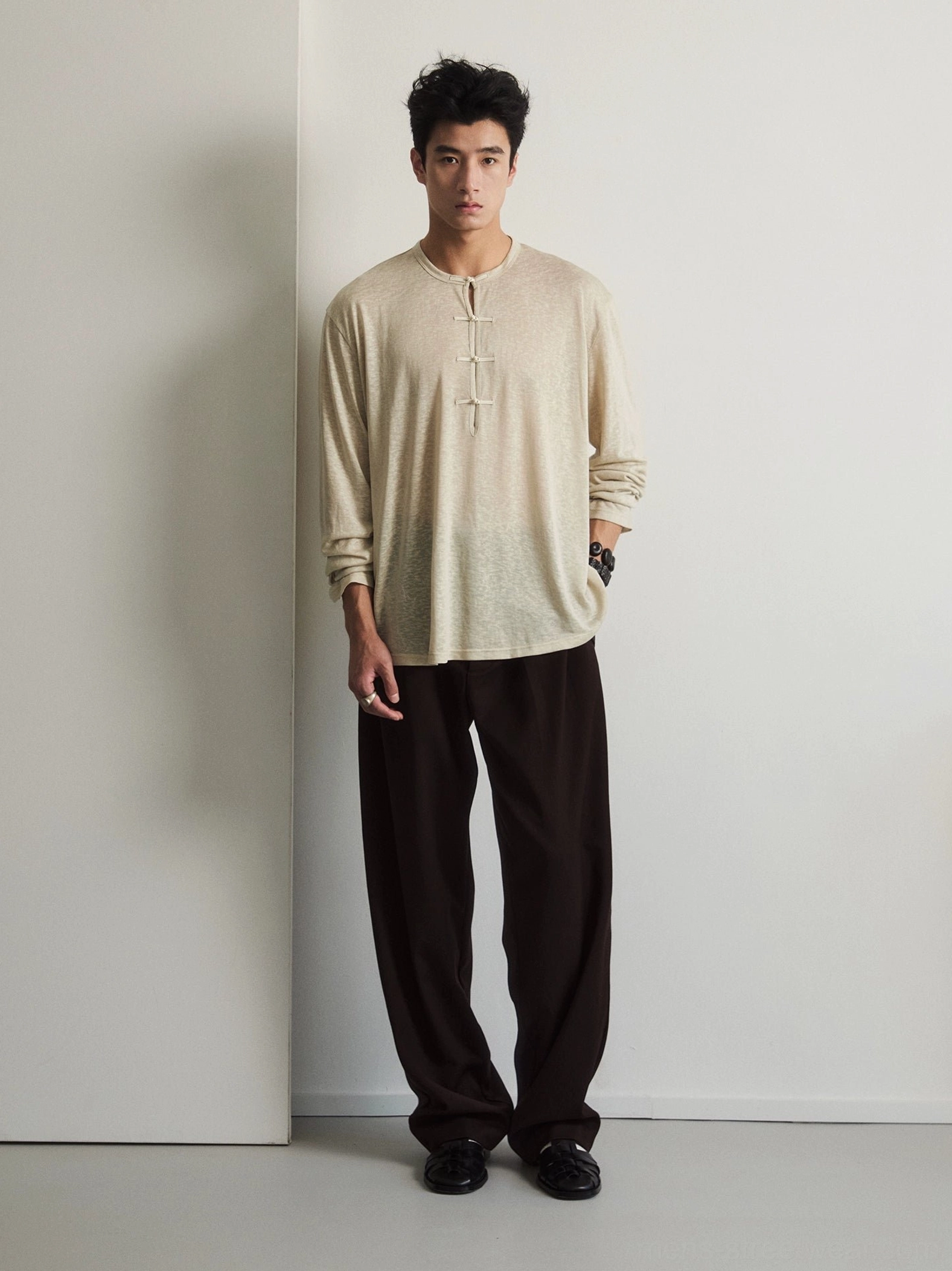 Men's oatmeal beige silk blend drape Henley long sleeve tee with frog button closures worn with brown wide leg trousers