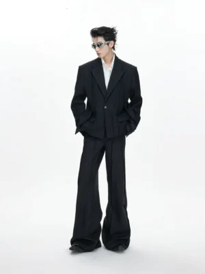 Men's oversized black pinstripe drape blazer and wide-leg trousers full front view in minimalist white studio
