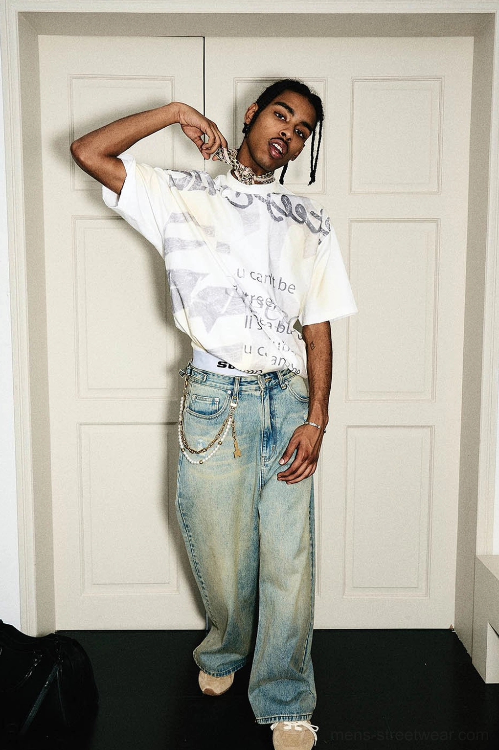 Full body side view of a men's oversized graphic T-shirt styled with vintage denim and casual streetwear accessories