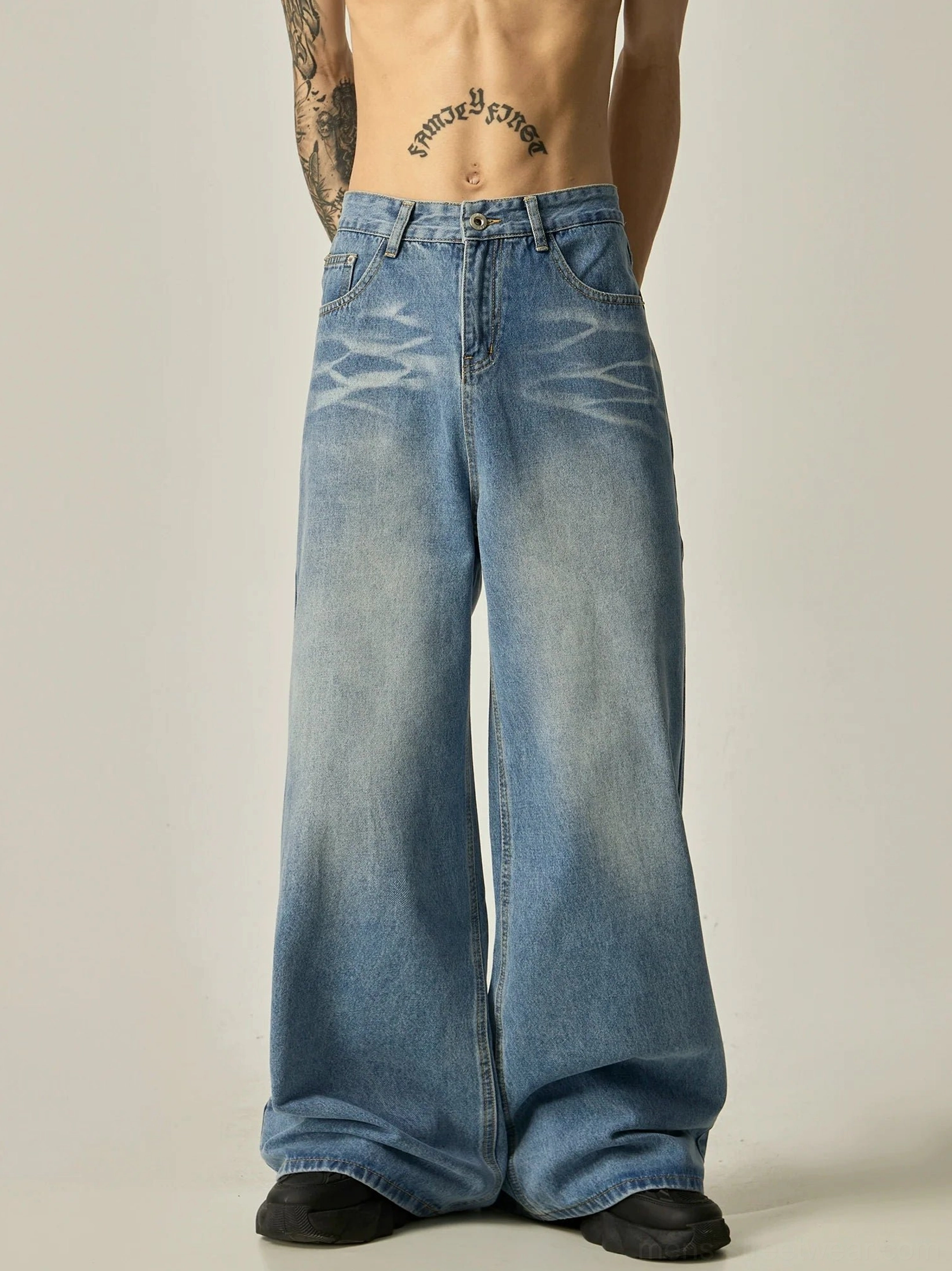 Front full-body view of men's oversized vintage wash blue wide-leg denim jeans with faded thigh details