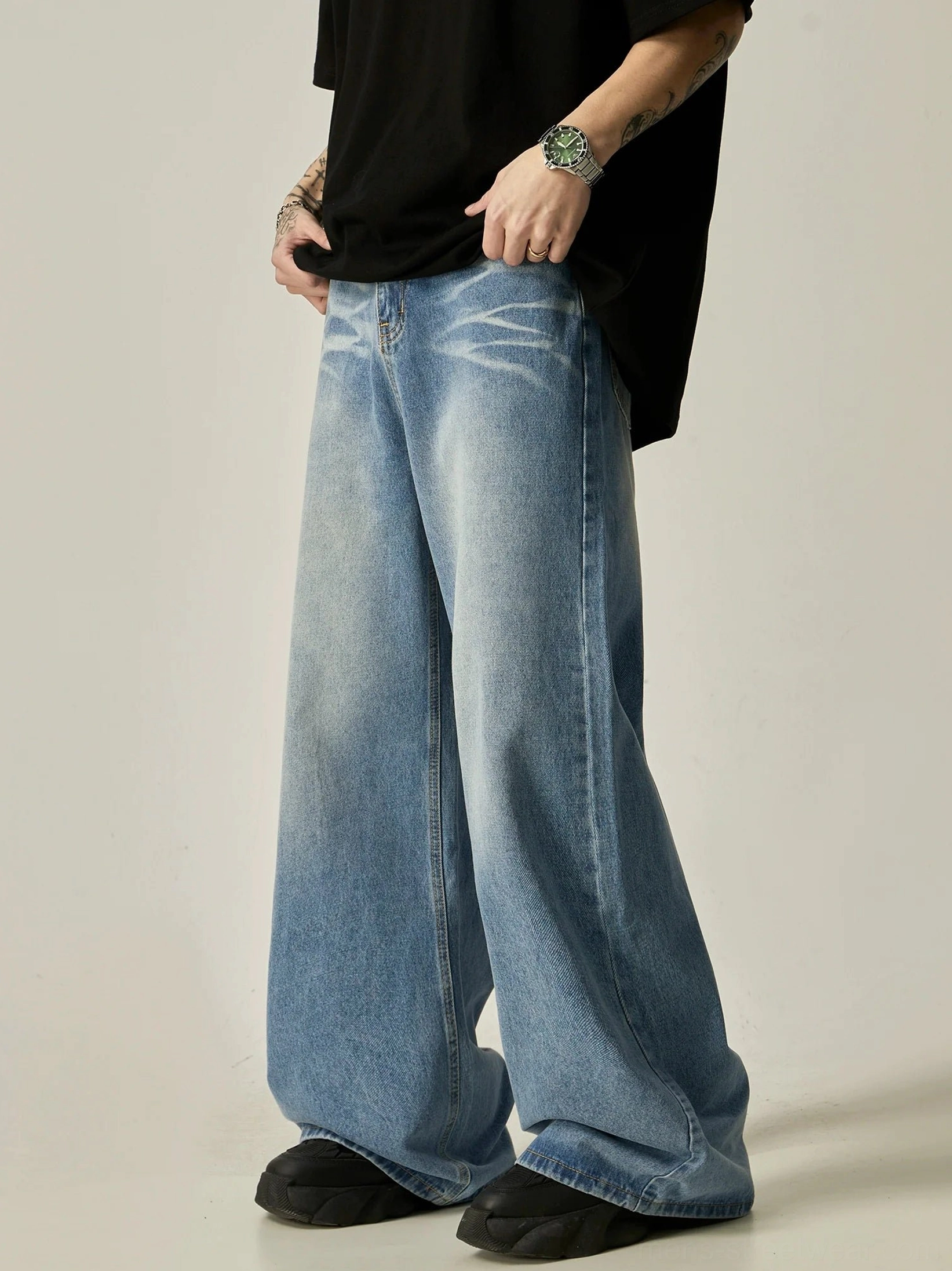 Side view of oversized vintage wash blue wide-leg jeans styled with a black oversized t-shirt and platform loafers