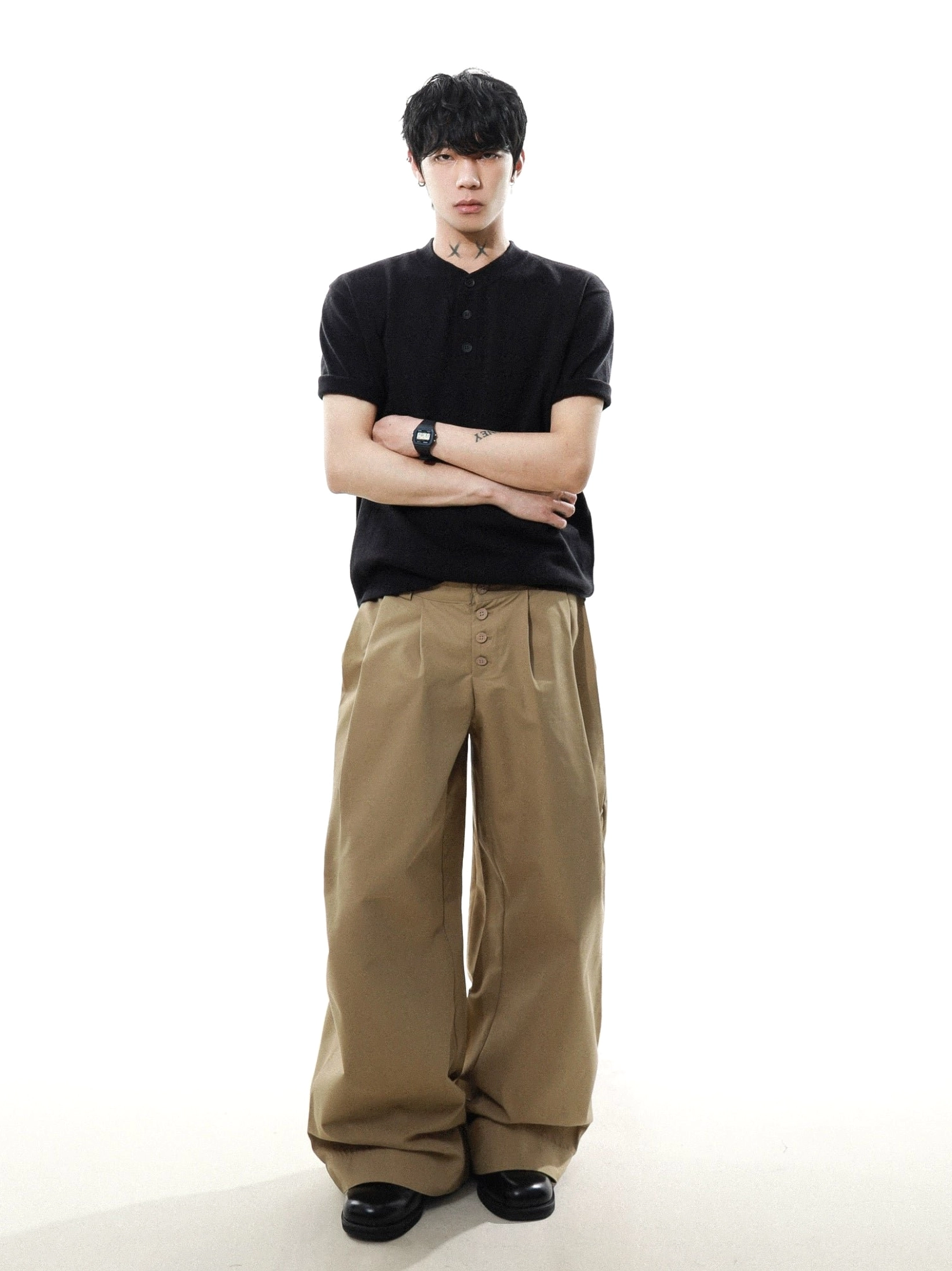 Full body front view of black relaxed knit Henley T-shirt styled with khaki wide-leg pants in minimalist streetwear look