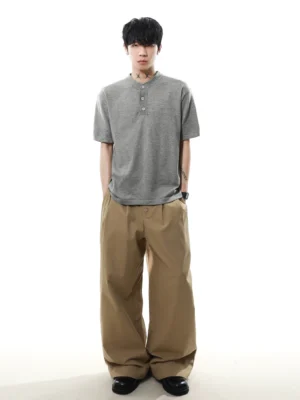Full body front view of model wearing heather gray relaxed knit Henley T-shirt with khaki wide-leg trousers