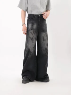 Three quarter front view of faded black wide leg jeans for men showing five pocket denim construction and storm wash