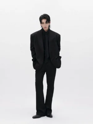 Front view of men’s structured black collarless blazer styled as a modern monochrome tailored streetwear outfit