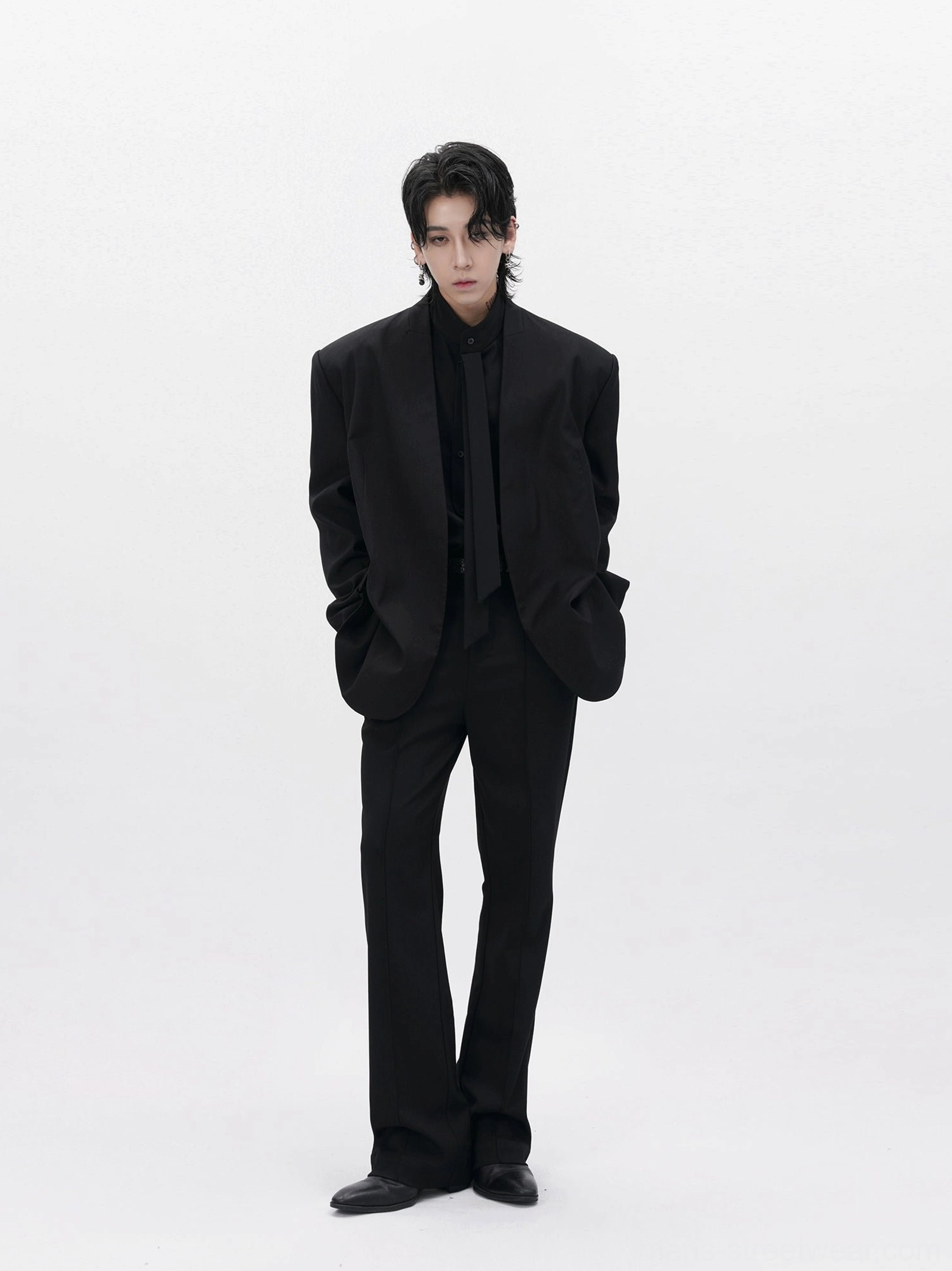 Front view of men’s structured black collarless blazer styled as a modern monochrome tailored streetwear outfit