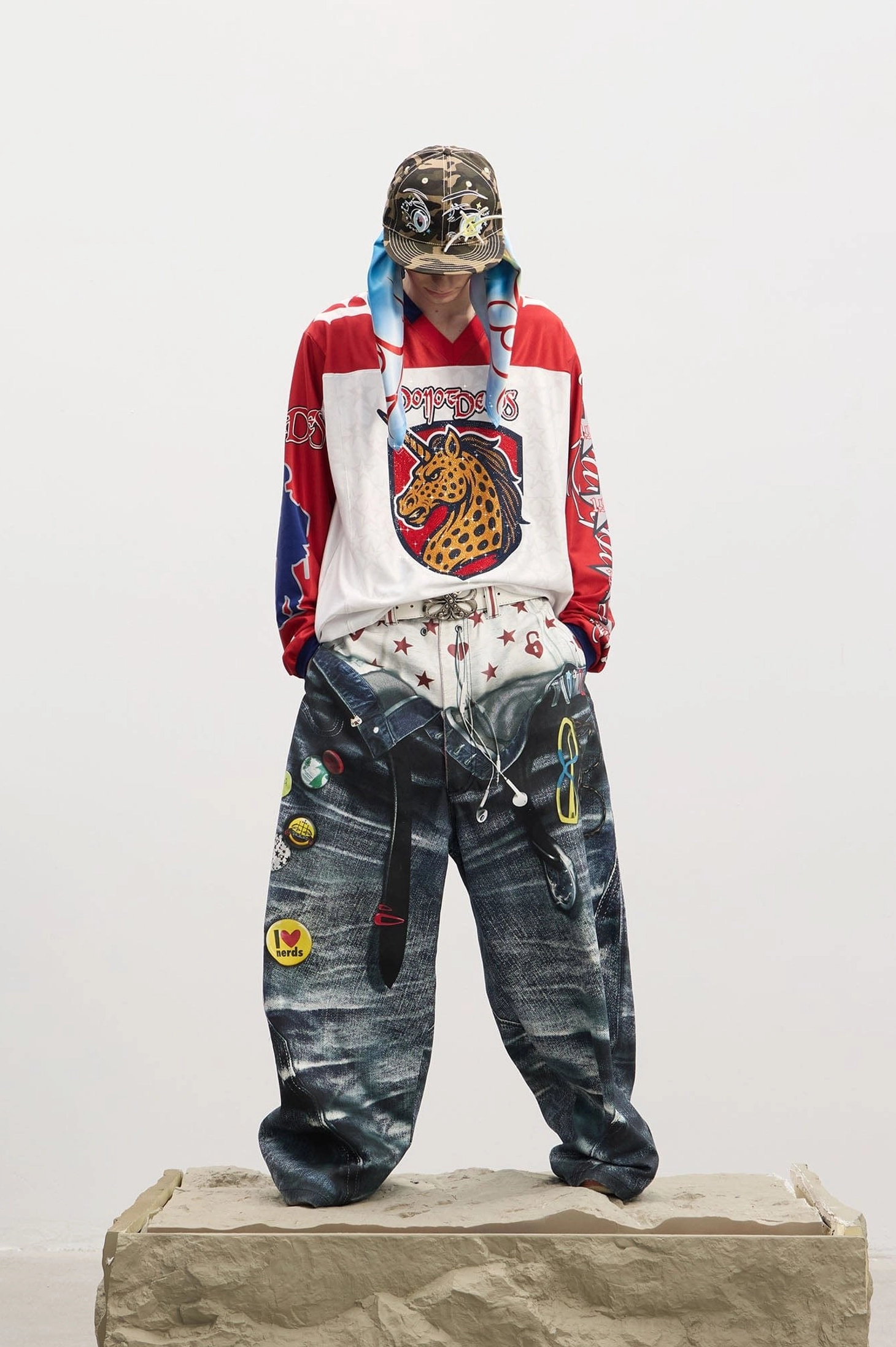 Front view of men's ultra-wide-leg Y2K jeans featuring printed boxer waistband, star and heart motifs, multiple enamel-style patches, and dark denim finish