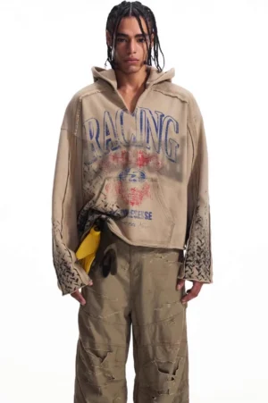 Men's vintage racing print hooded sweatshirt shown from the front with faded khaki color, exposed seam details, kangaroo pocket, and oversized streetwear fit