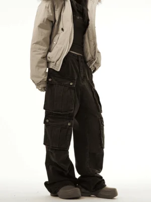 Men's vintage washed cargo denim jeans shown from a left angled view with stacked utility pockets and a relaxed wide-leg streetwear fit