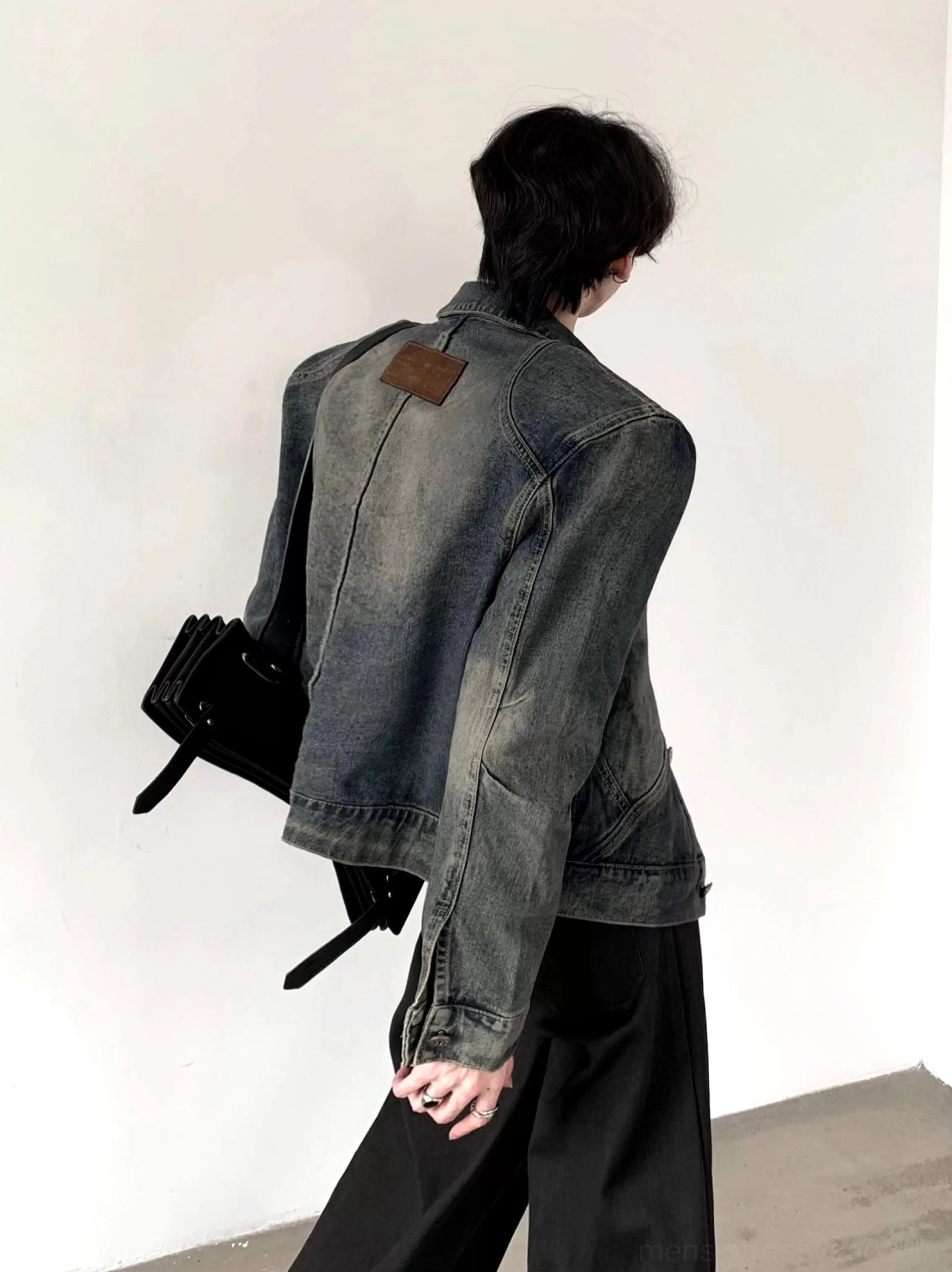 Back three-quarter view of men's vintage washed denim trucker jacket featuring faded blue finish and brown back yoke patch