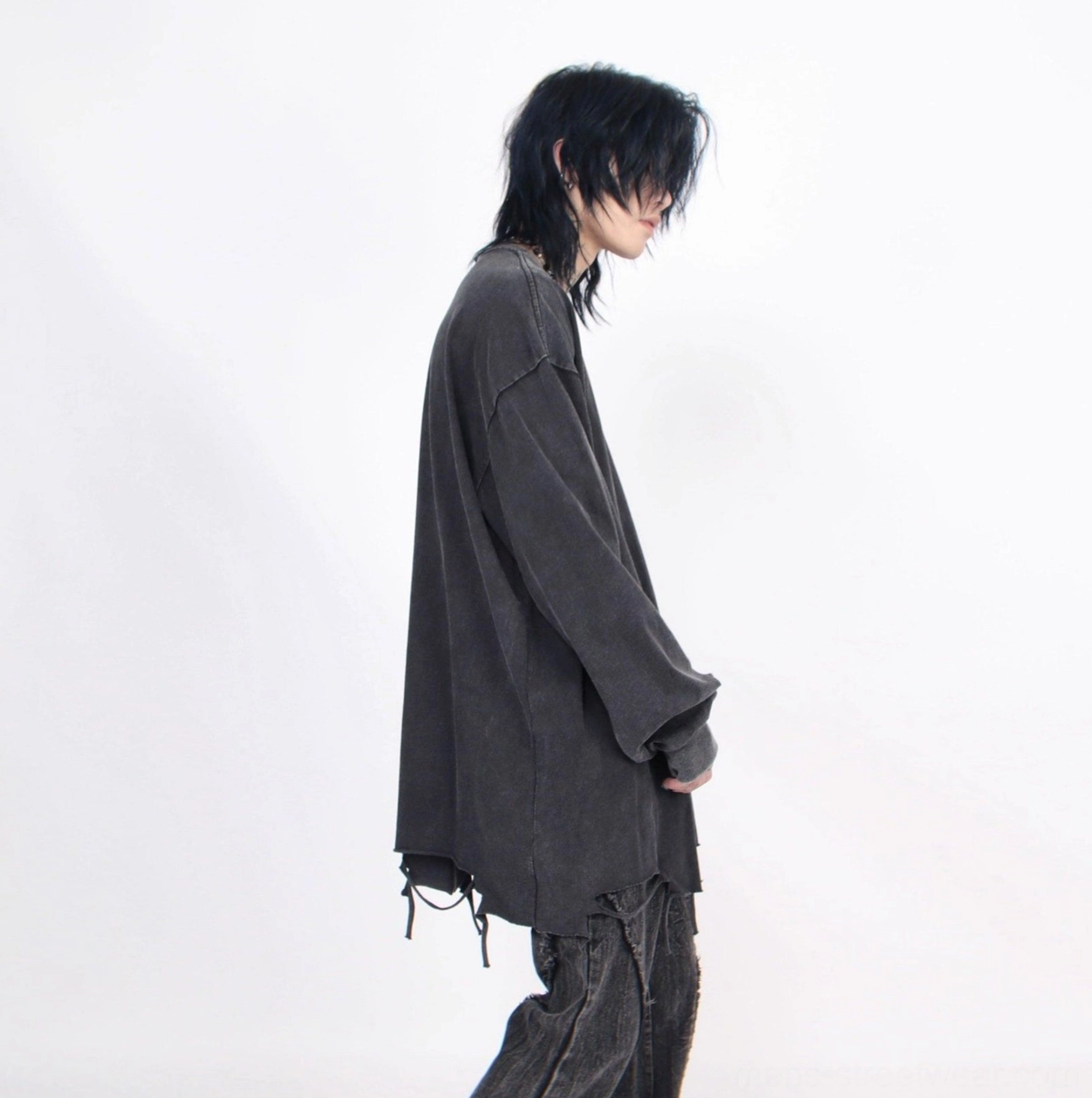 Side profile of men's washed black distressed oversized long-sleeve tee with raw frayed hem