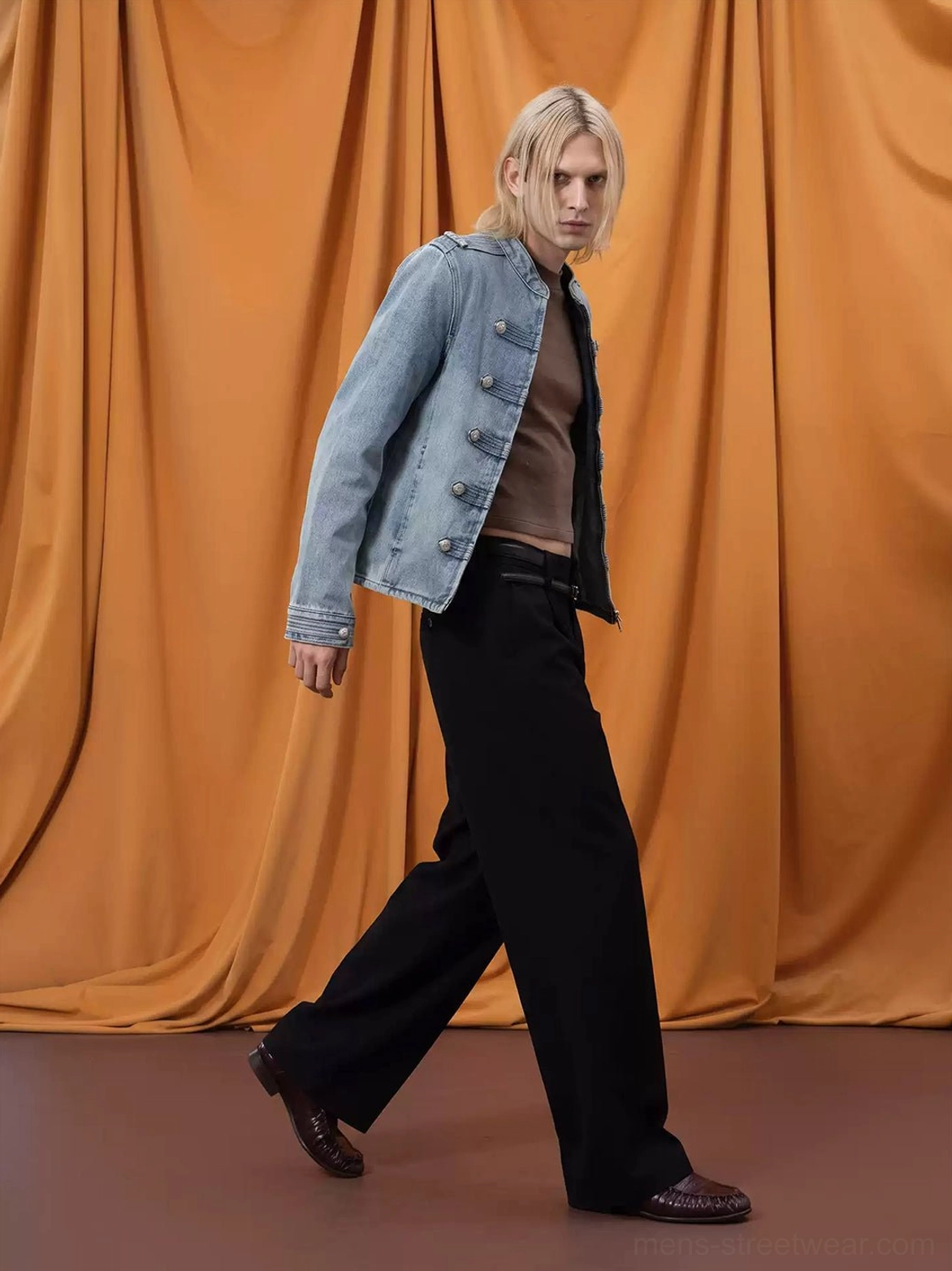Side view of mens washed denim military epaulette jacket worn unzipped showing lining and buttoned sleeve cuff