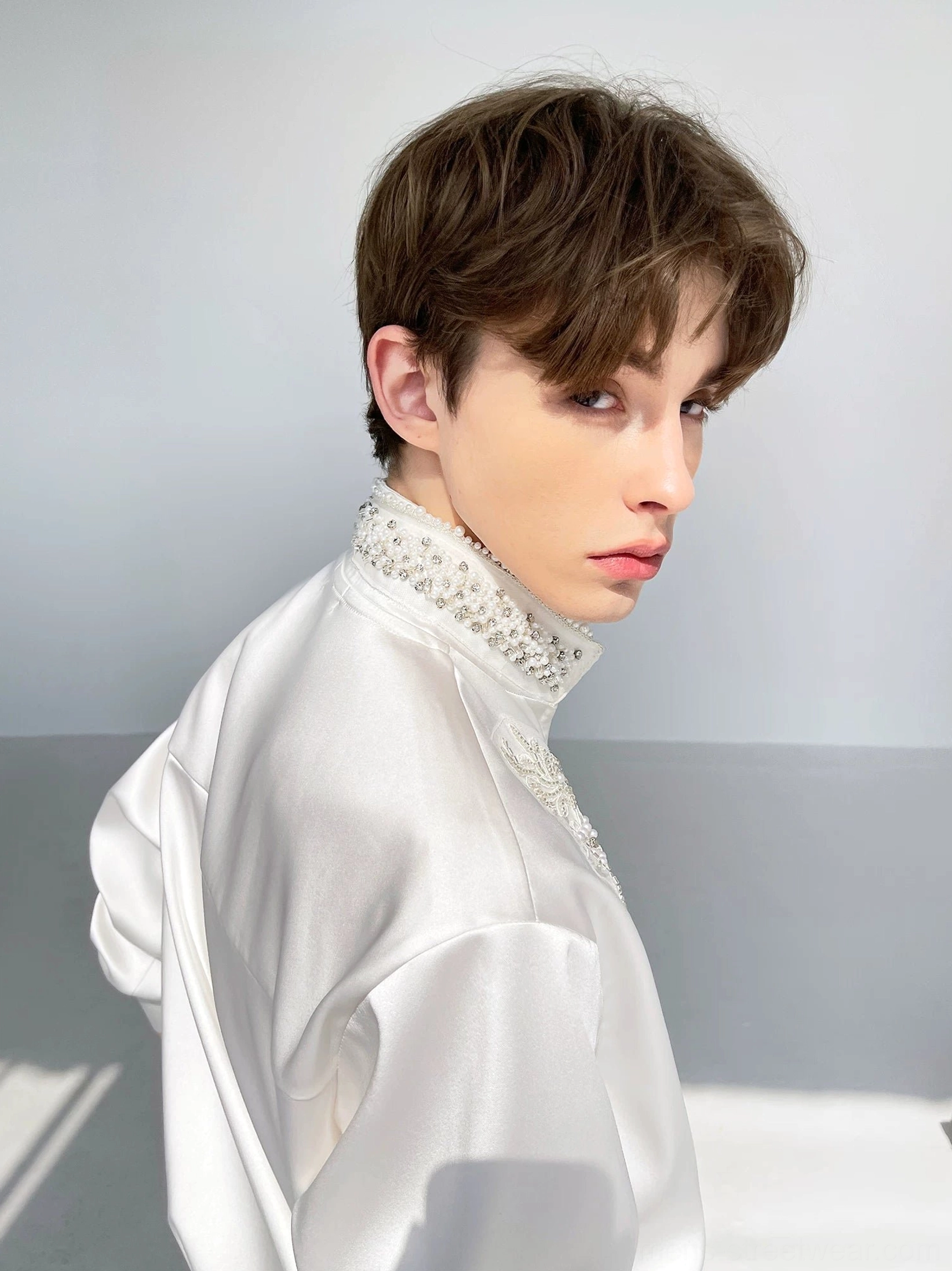 Men's white beaded floral embroidered satin shirt shown from the rear three-quarter view with glossy fabric and stand collar
