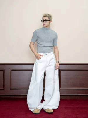 Men's white curved seam wide leg baggy denim jeans front three-quarter view with grey knit top and loafers