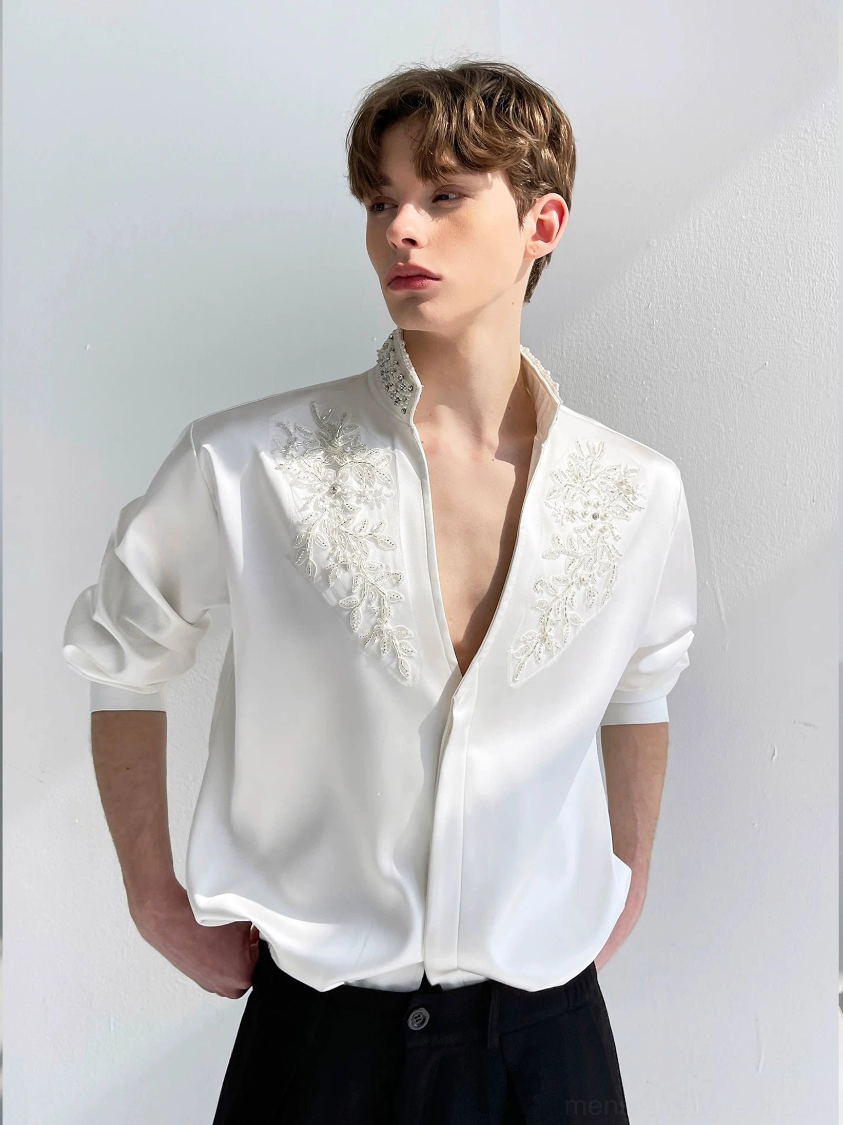 Men's white floral embroidered satin V-neck shirt styled with black tailored trousers in a front full upper-body view