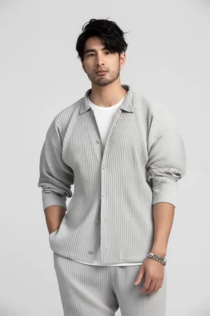 Men's white gray vertical pleated stripe button-up shirt styled open over a white undershirt in a studio front three-quarter view