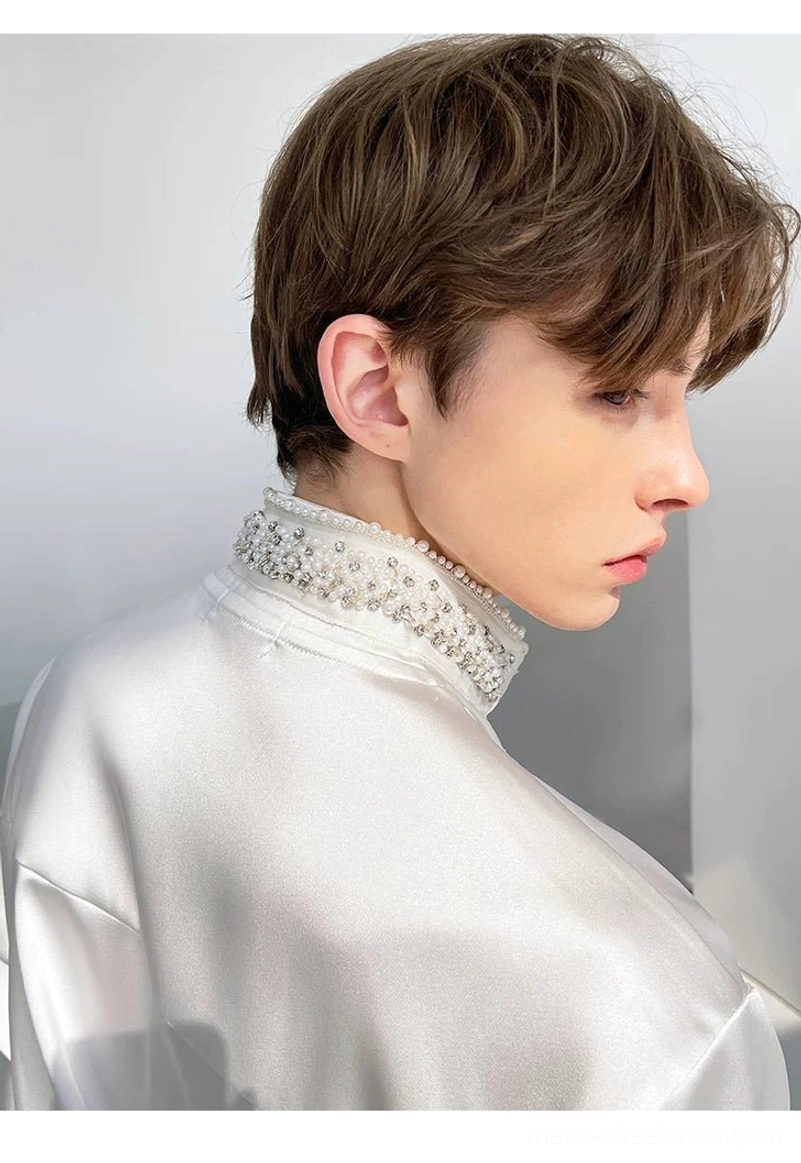 Close-up of intricate beaded trim on the stand collar of a men's glossy white satin shirt