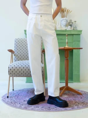 Men's white straight-leg denim jeans rear three-quarter view styled with black platform boots in a retro studio