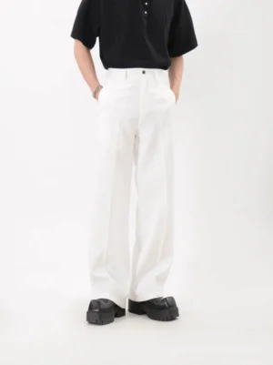 Men's white tailored wide leg trousers with pressed front creases shown from the front in a minimalist studio