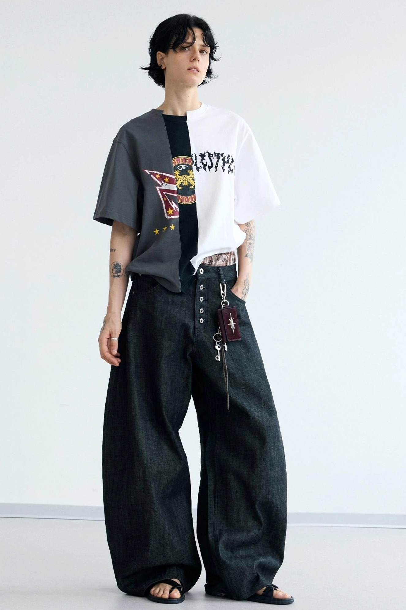 Relaxed front view of men's wide-leg black denim jeans featuring an exposed plaid inner waistband and oversized streetwear cut