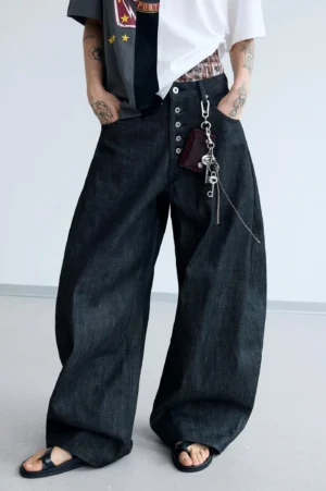 Front full-body view of men's dark washed black wide-leg curved knife jeans with exposed button fly and attached denim keychain wallet