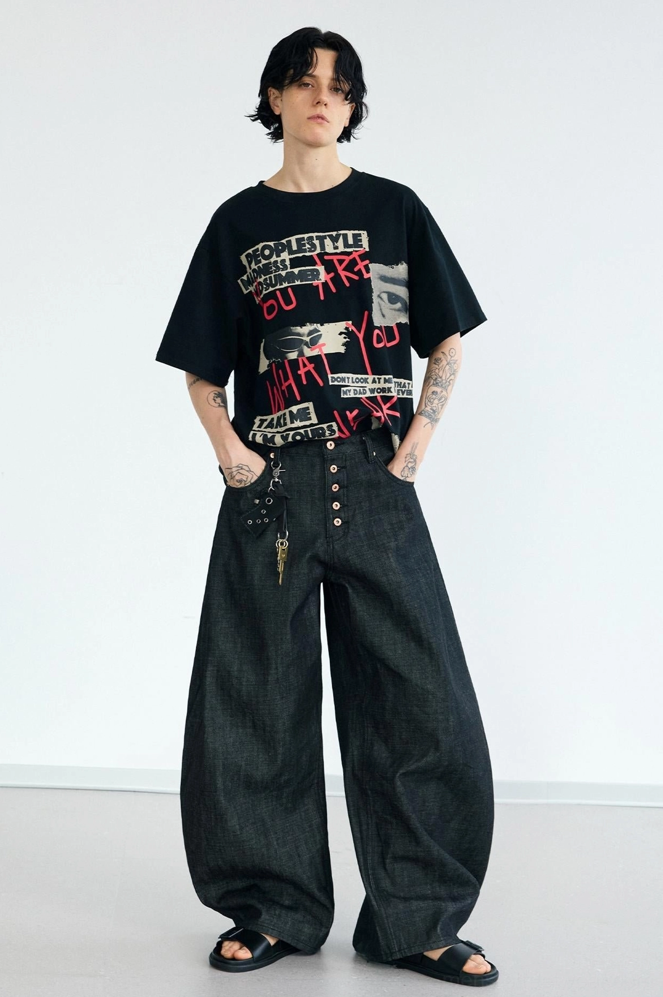 Men's wide-leg curved knife jeans with dark washed denim, buckle detail, exposed button fly, and contemporary streetwear styling