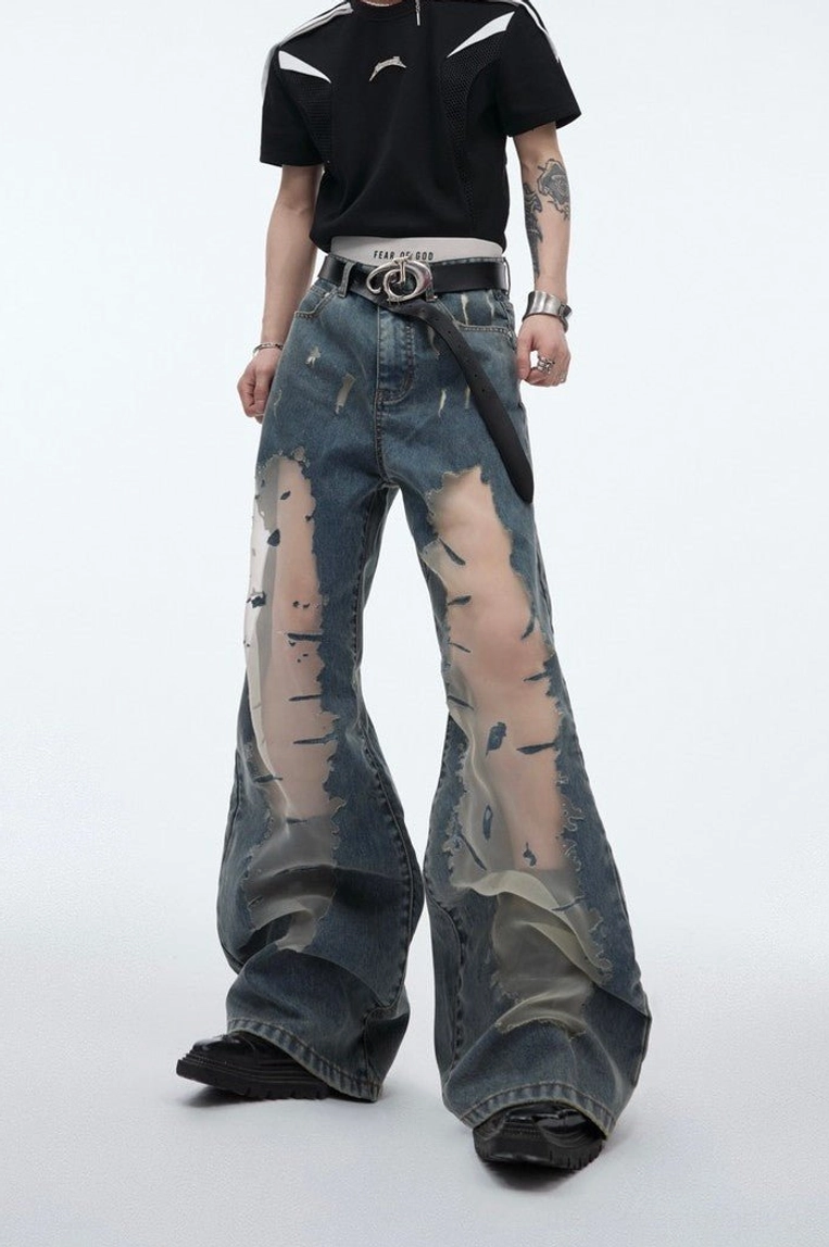 Front three quarter view of blue mesh panel distressed relaxed fit wide leg jeans with vintage washed denim and frayed thigh cutouts